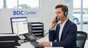 BDC representative at dealership workstation handling inbound call with CRM system visible